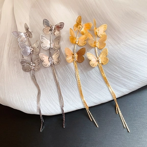 Detailed macro view of gold and silver butterfly tassel earrings with sparkling zircon