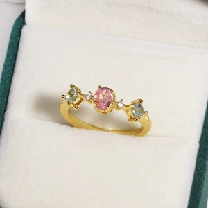 Macro view of gold flower ring with pink oval stone and colorful zircon in jewelry box