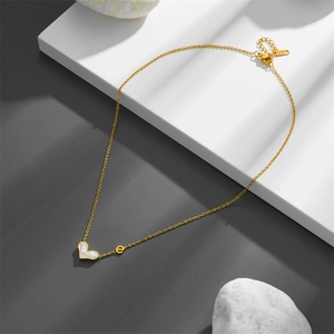 Golden heart necklace with white shell inlay and letter e charm on geometric background