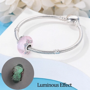 Macro view of silver snake chain bracelet with luminous pink beads and green glow effect