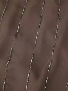 Macro shot of silver beaded vertical lines on dark brown sequined summer dress fabric