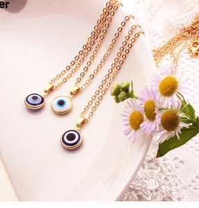 Detailed view of three gold evil eye pendants in dark blue, light blue and black on a tray