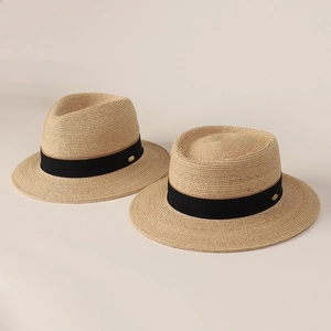 Detailed texture of Raffia straw hats with black grosgrain ribbon and golden logo plate