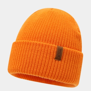 Close-up of bright orange ribbed knit beanie with brown faux leather logo patch
