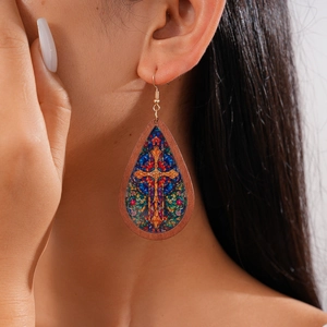 Close-up of wooden teardrop earring with stained glass cross pattern on female model