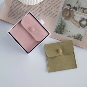 Détail de pochettes à bijoux en microfibre rose et vert avec bouton-pression et boîte.