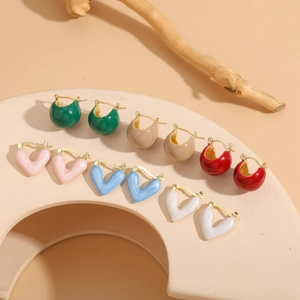 Detail shot of colorful enamel heart and dome earrings on elegant stone props