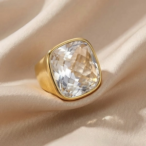 Macro detail of a large square-cut crystal ring with a polished gold-tone wide band