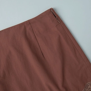 Close-up of the hidden side zipper and delicate lace trim on this brown mini skirt