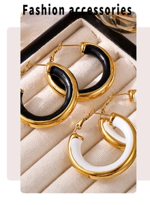Detail of chunky gold-plated hoop earrings with black and white enamel inlays