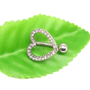 Close-up of a silver heart-shaped belly button ring with crystals on a green leaf