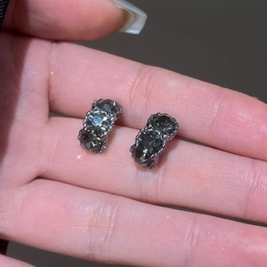 Detalle de pendientes de tres niveles con cristal gris humo sobre una mano