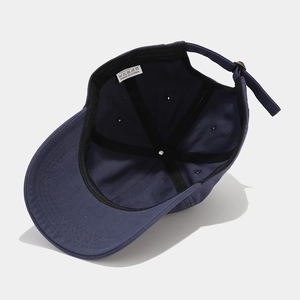 Internal view of a navy cotton baseball cap showing adjustable buckle and 100% cotton label