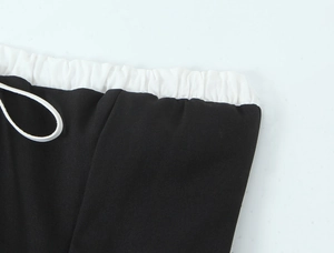 Detail of contrast white elastic waistband and drawstring on black mini dress
