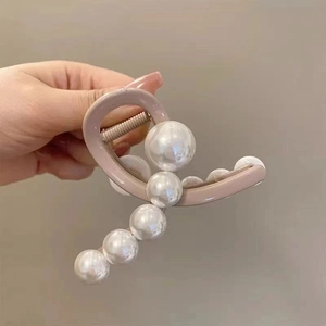 Detailed view of pink hair claw clip with elegant white pearls and metal spring