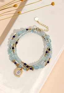 Detailed view of multi-layer beaded necklace with blue stones and a gold square pendant