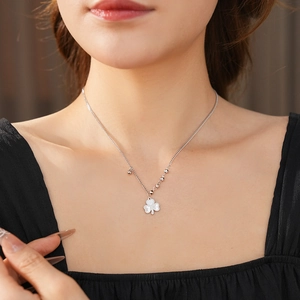 Detail of silver beaded chain necklace with clover pendant on model neck