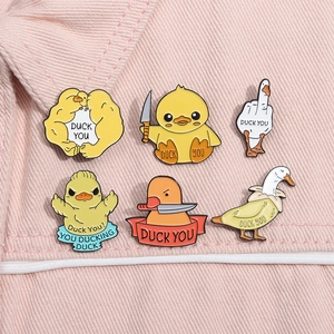 Detailed view of six funny duck enamel pins with humorous slogans on pink denim fabric