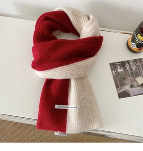 Detail of red and cream patchwork knitted scarf with vertical ribbed texture and white label