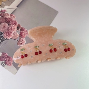 Detailed shot of pink marble acetate hair claw with red cherry and rhinestone embellishments