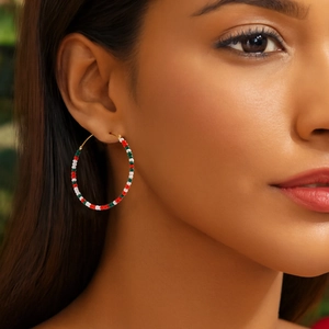 Close-up of bohemian hoop earrings with red, white, and green beads on a gold ring