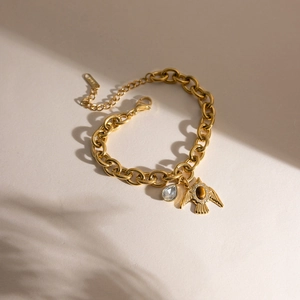 Detailaufnahme des goldenen Gliederkettenarmbands mit Tigerauge-Vogel und Tropfenanhänger