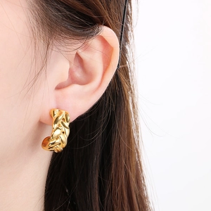 Boucles d'oreilles en U en acier titane plaqué or 18 carats portées par un modèle