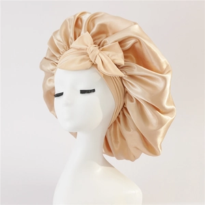 Detailed view of champagne satin sleep bonnet with bow tie on a white mannequin head