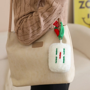 Detail of Mahjong tile plush keychain featuring red and green embroidery on a tote bag