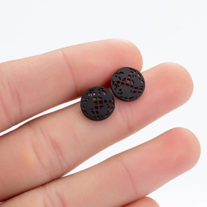 Detailed view of black round geometric earrings held to show 10mm size and hollow texture