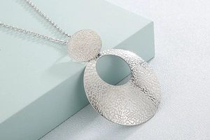 Macro shot of silver stainless steel necklace with hammered texture double disc pendant