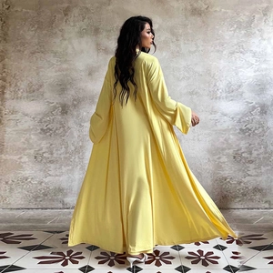 Robe longue fluide jaune élégante à manches longues vue de côté en intérieur de luxe