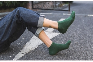 Close-up of dark green breathable cotton knit socks worn in an outdoor casual setting