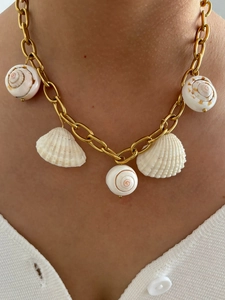 Close-up of golden chunky chain necklace with natural seashell pendants on model
