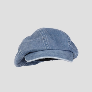 Detailed close-up of blue denim newsboy cap featuring white stitching and washed texture