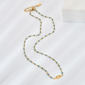 Détail macro d'un collier doré avec des perles bleues et un pendentif oeil évidé