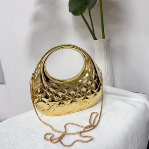 Détail d'une pochette coquillage dorée avec pierres d'émeraude et chaîne