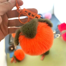 Detail of plush orange persimmon keychain with green leaf and metal clip ornament