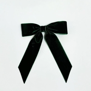 Detailed texture of a dark green velvet bow hair clip on a clean white background