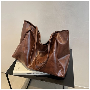 Detail view of large brown vintage tote bag made of textured soft leather on a stand