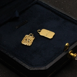 Detailed shot of gold butterfly relief and Beauty engraved pendants in velvet box