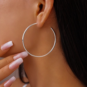 Detailed view of large silver C-shaped hoop earrings on model with high gloss finish