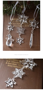 Detail of clear acrylic snowflake and icicle ornaments on vintage books with pine branches
