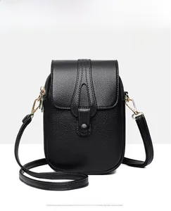 Detail of black lychee grain leather mini crossbody bag with gold hardware and strap