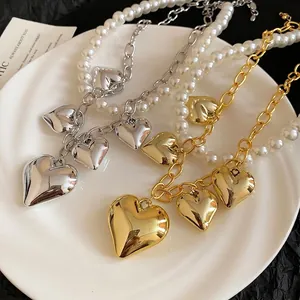 Vintage heart pearl necklace featuring asymmetric gold and silver metal chains on porcelain
