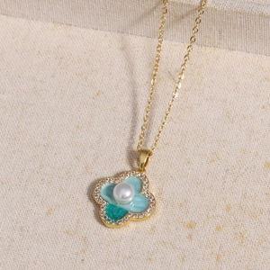 Detail of clover pendant with green enamel, central pearl and pavé crystals on gold chain