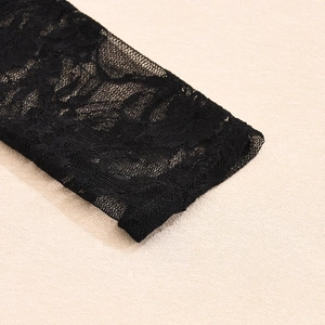 Primer plano del puño de encaje negro con intrincado patrón floral sobre fondo beige