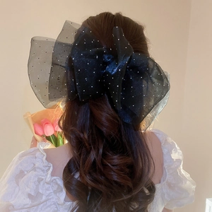 Détail d'une grande pince à cheveux avec nœud en maille noire et strass scintillants
