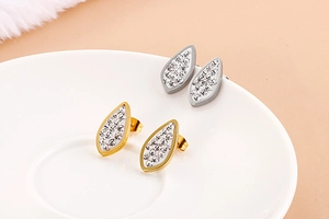 Detail of 18K gold and silver teardrop earrings with crystals on ceramic tray