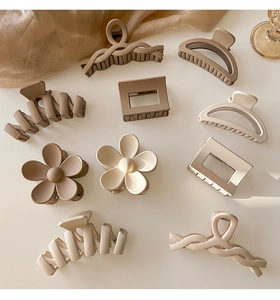 Flat lay of multiple matte hair claws in coffee, beige and cream colors on silk fabric